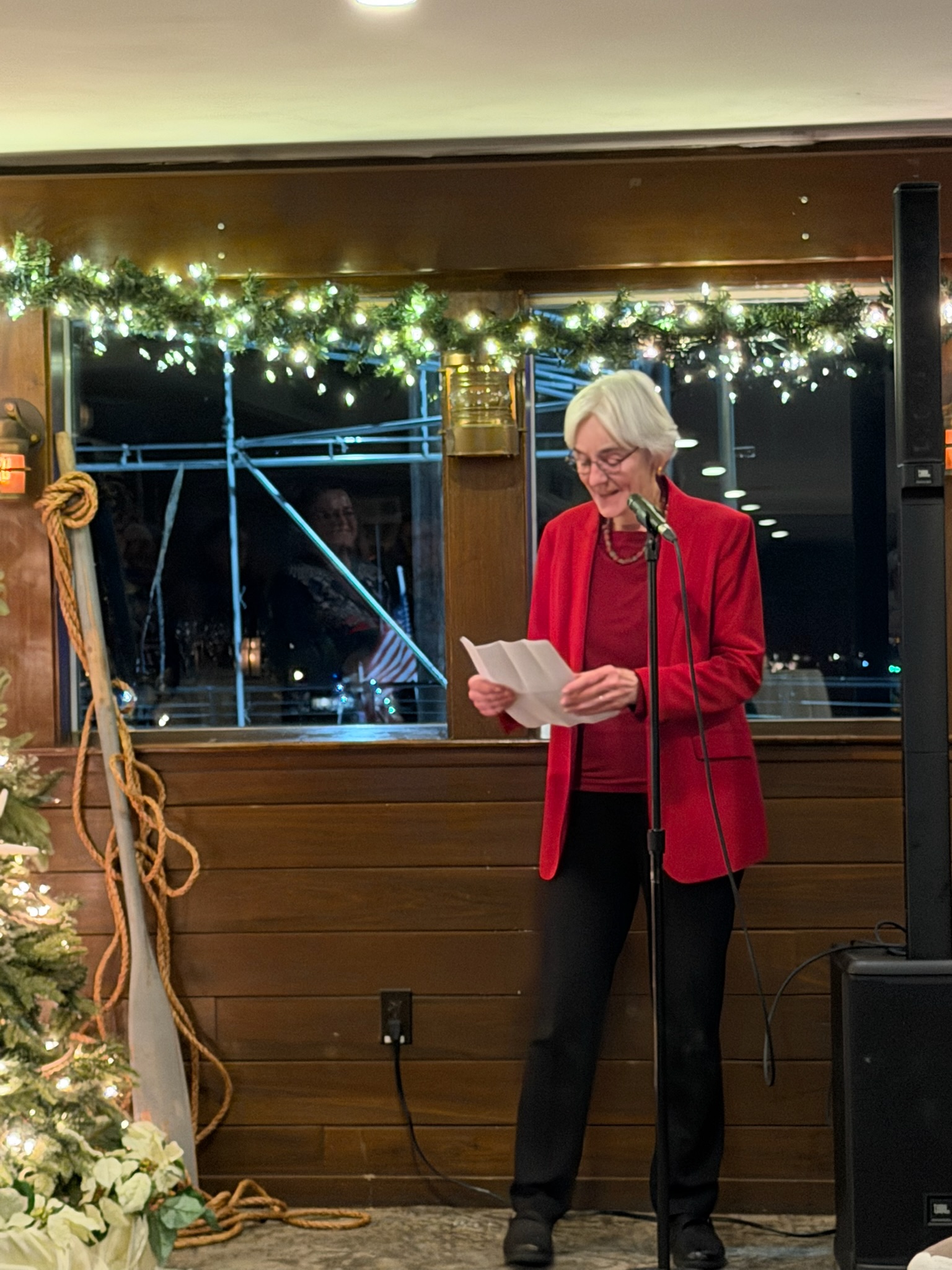 Jenny Wriggins giving a speech at her retirement party in front of christmas lights.