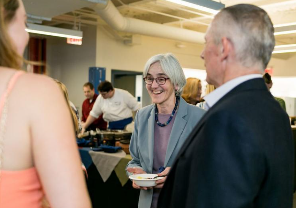 Wriggins smiling and holding a bowl of food at an event.