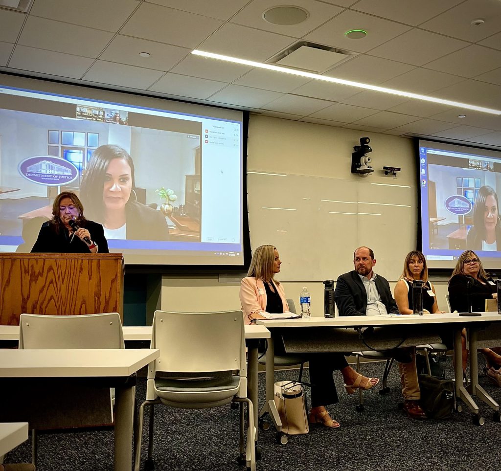 Photo of Dean Saufley speaking in front of the room next to table of panelists.